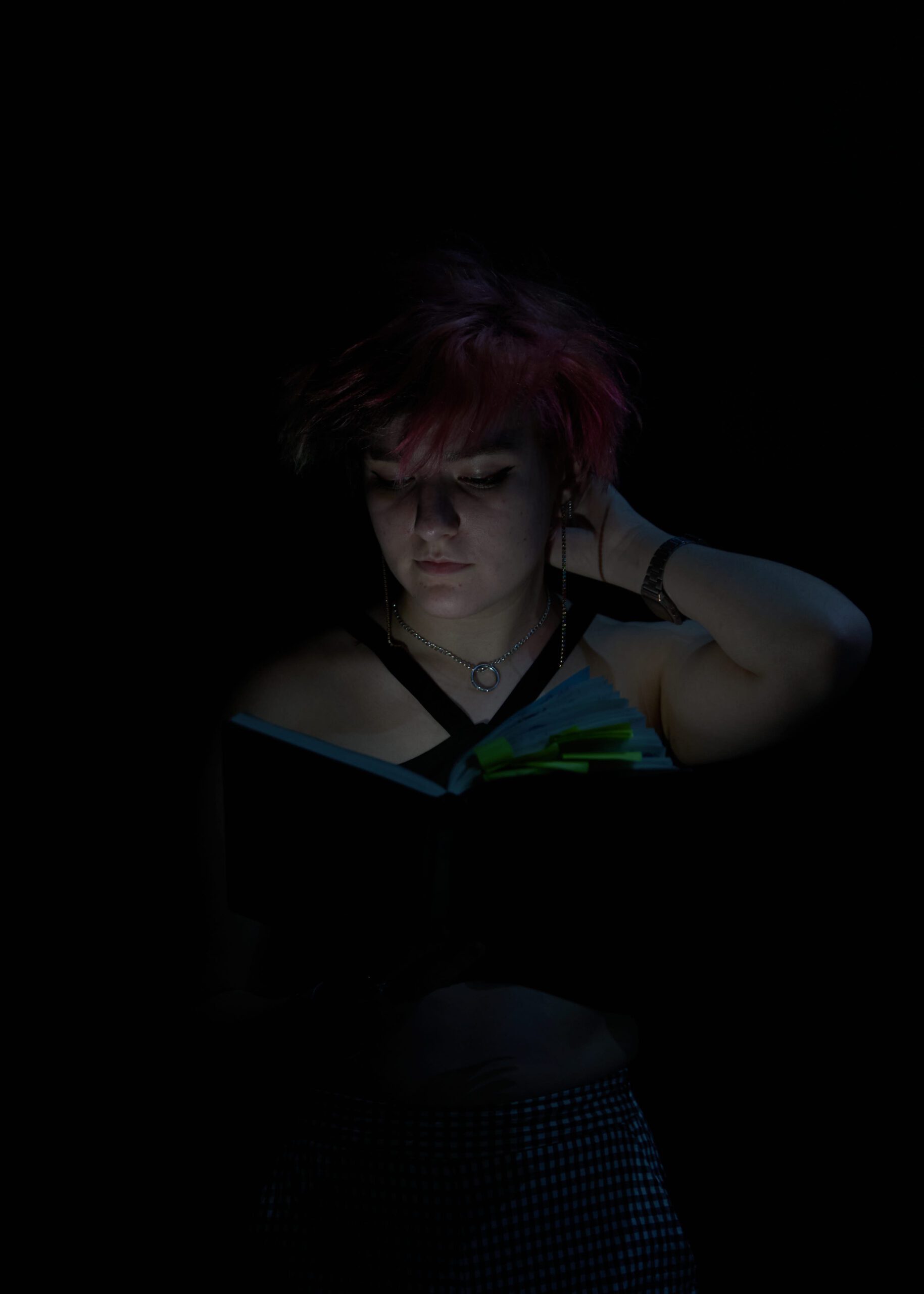 Joven de cabello rosa leyendo libro