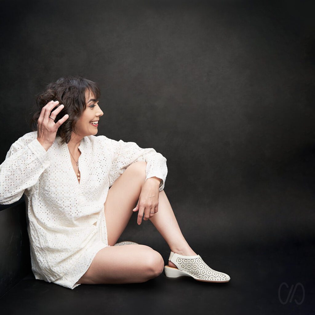 7 Tips de Retrato para Lucir más Joven como esta mujer vestida de blanco sentada en el suelo