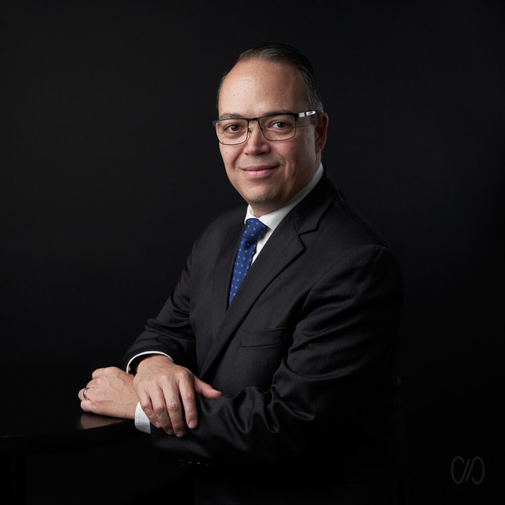 Fotografía Profesional Monterrey de empresario recargado sobre mesa usando traje nero y corbata azul