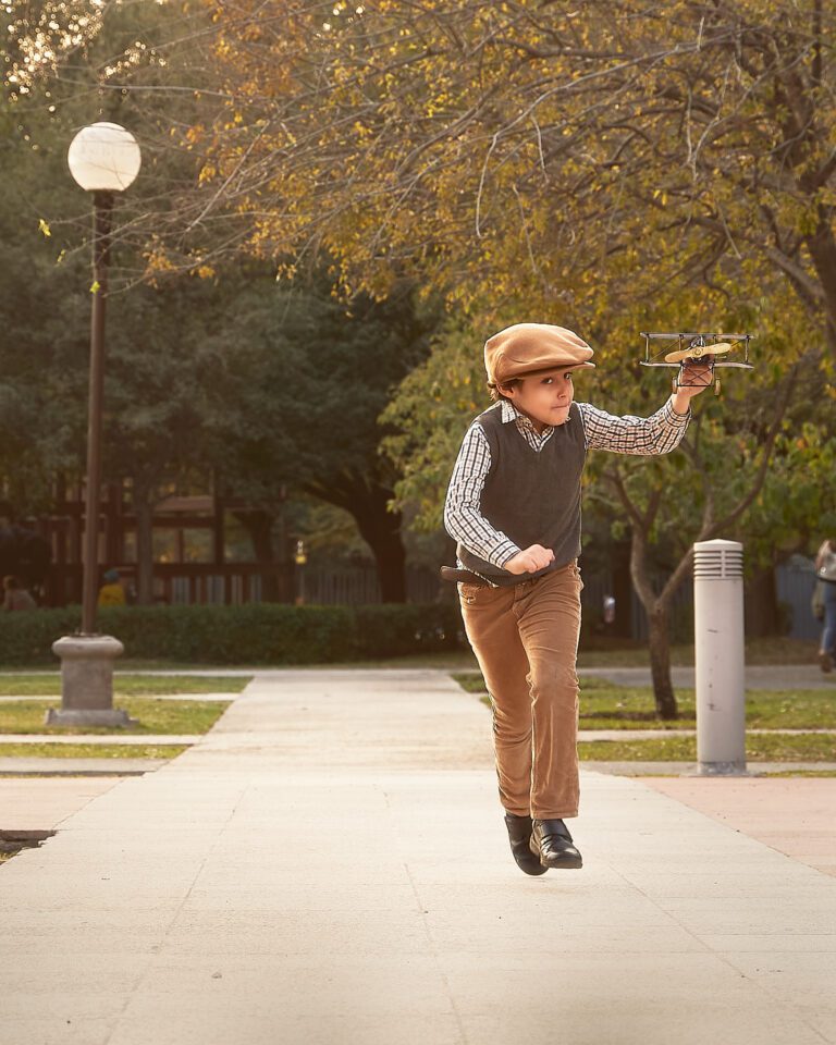 Fotografía Fine Art de niño corriendo con avión de juguete en la mano en un parque