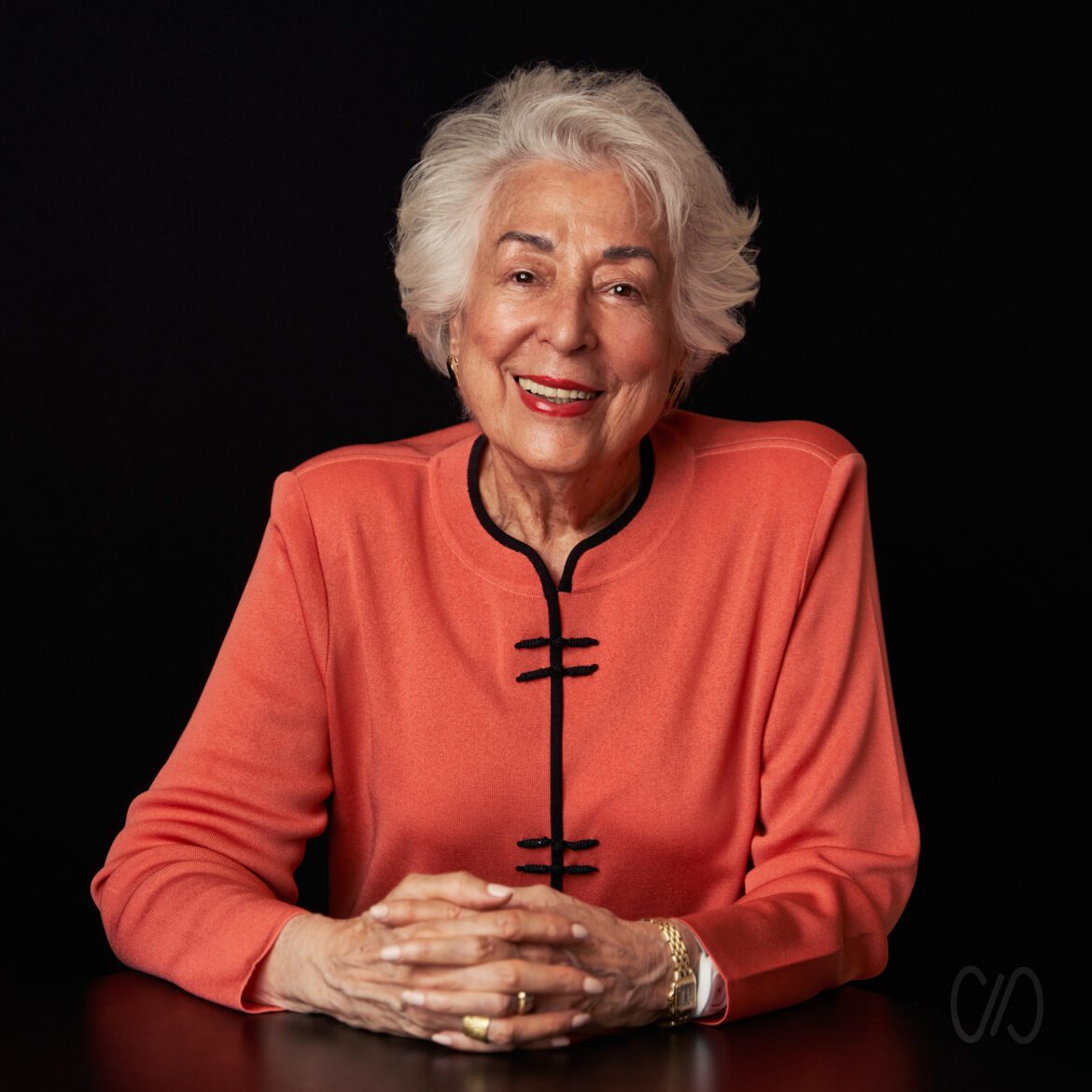 Mujer de 80 años sonriente de cabello canoso y blusa color bermellón