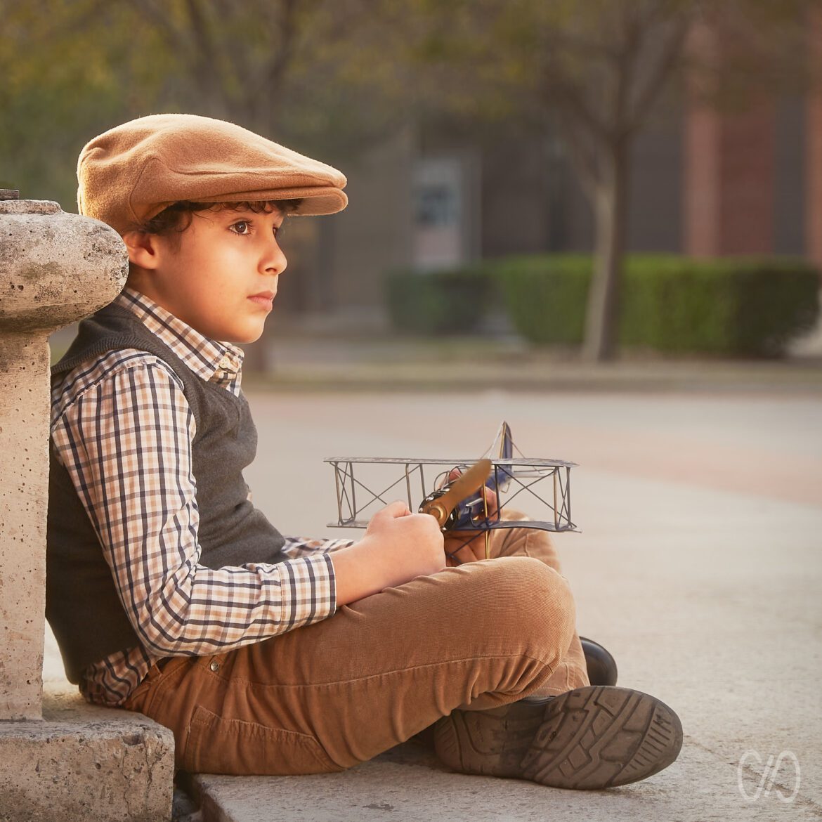 Retrato Fine Art Infantil de niño sentado con avión de juguete en las manos y usando una boina en la cabeza