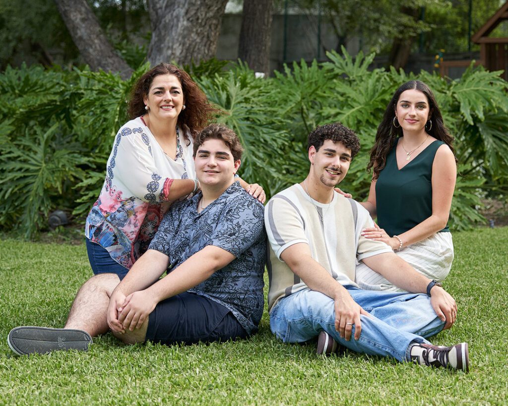 Madre de 50 años con sus 3 hijos adolecentes en un jardin sentados