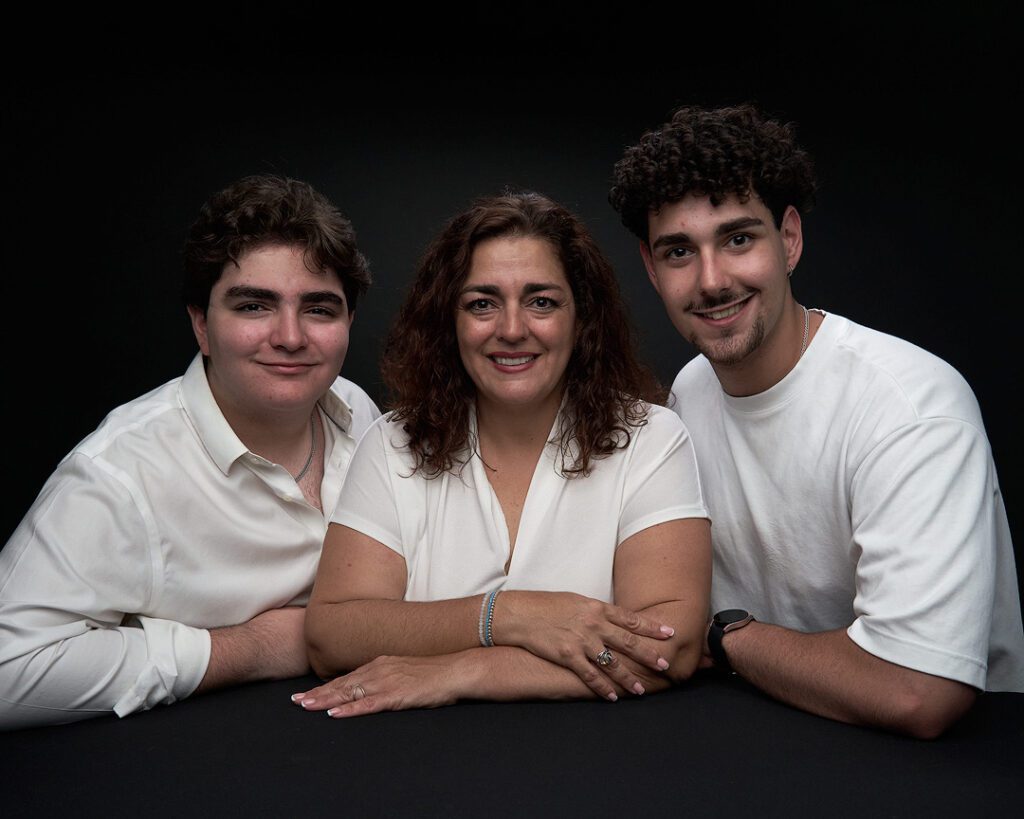 Foto de estudio en fondo negro de una madre con sus dos hijos