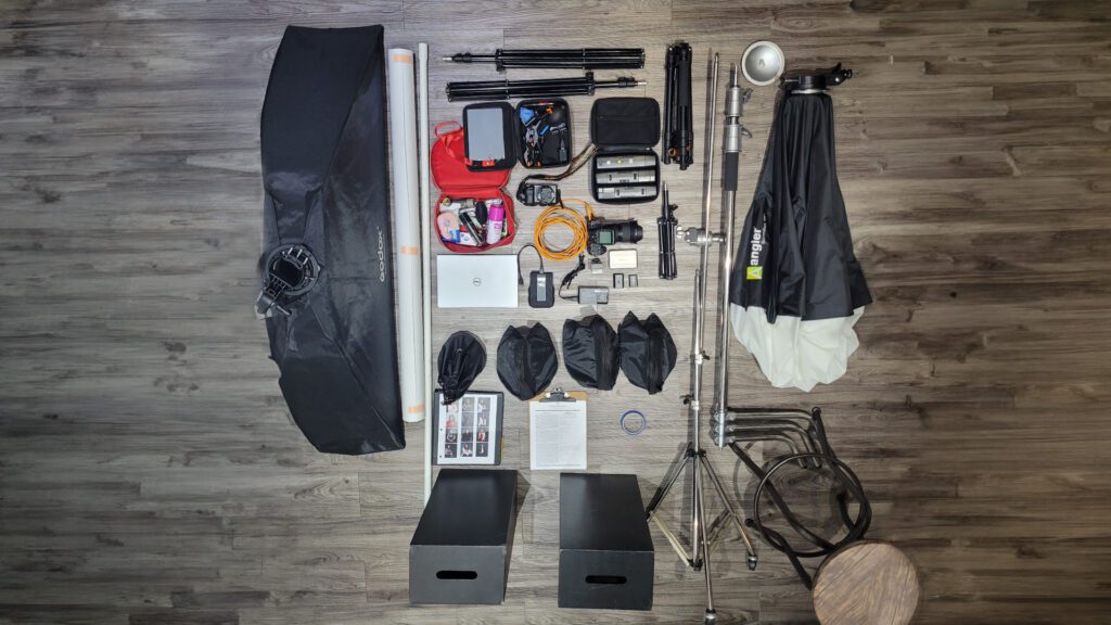 Foto aerea del equipo fotográfico que se requiere para una sesión fuera del estudio, incluye cámara, soft box, flash, banco, bolsas de arena, c stand y otros