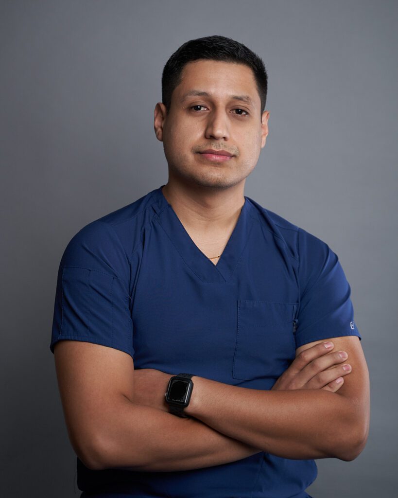 Retrato de cuerpo entero de hombre joven en pose casual con amplia sonrisa  y brazos cruzados, mirando hacia atrás