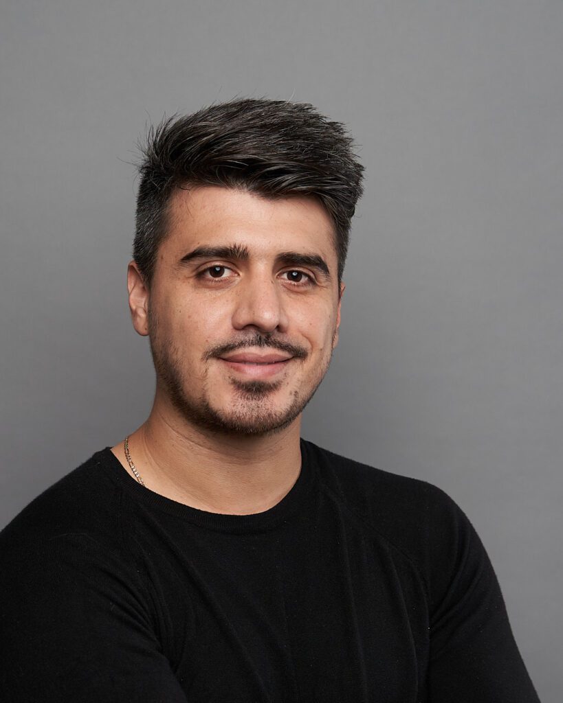 hombre con playera negra, mostrando una ligera sonrisa principalmente con sus ojos