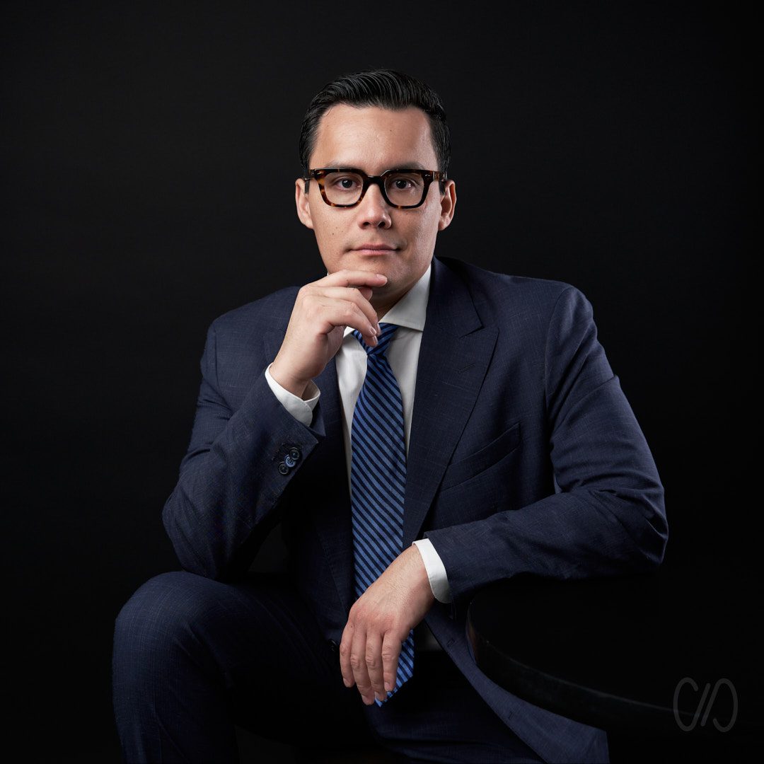 Porque es importante tener foto de perfil en LinkedIn 2024 Empresario con lentes y traje azul recargado sobre su mano derecha
