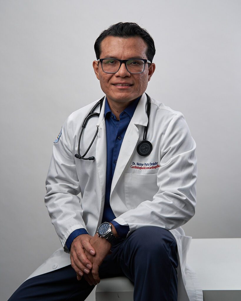 Médico sentado con bata y estetoscopio, con las manos juntas un poco encorbado y las manos mostrando inseguiridad