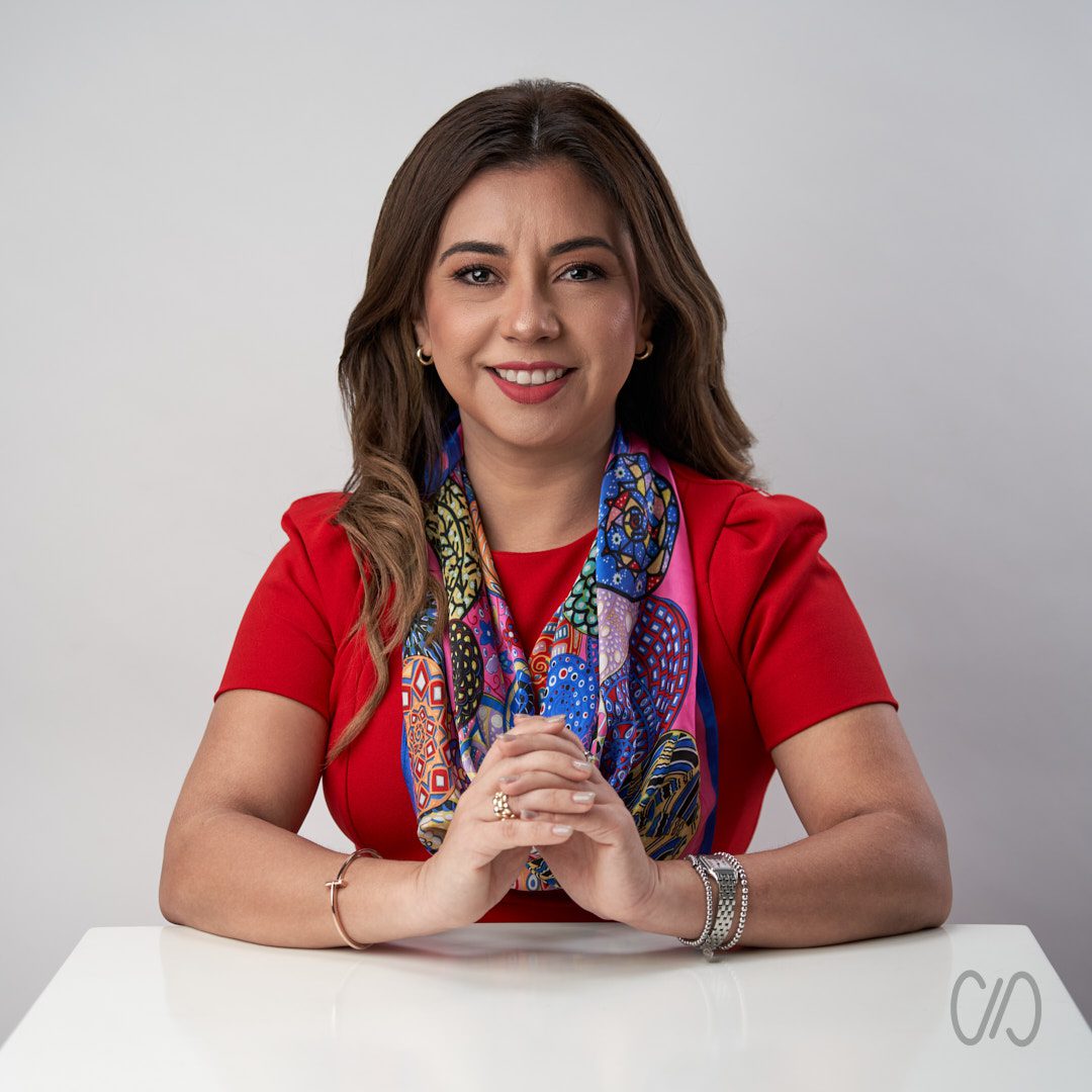 Cómo Prepararte Para Una Sesión de Fotos de Perfil Profesional en Monterrey con foto de mujer con vestido rojo apoyada sobre una mesa con las manos entrelazadas