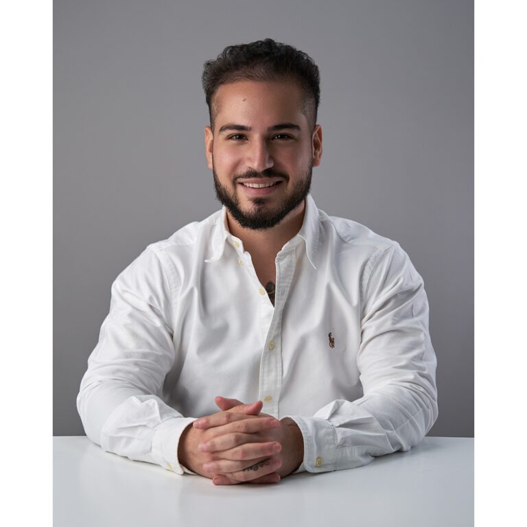 Precio Paquetes Fotos Perfil Profesional en Monterrey de joven con camisa blanca recargado sobre mesa blanca y fondo gris