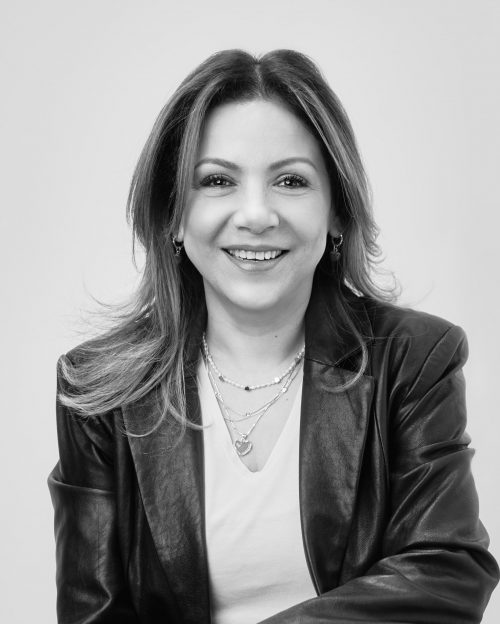 Foto de perfil profesional de sonriente mujer con cabello largo y saco de piel tomada en blanco y negro